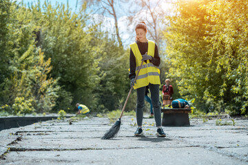 pretty volunteer female cleaning up park from dust waste and foliage
