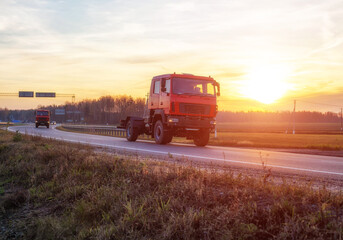 Off-road special equipment drives along the highway against the backdrop of a sunny sunset. Summer nature, copy space for text, industry