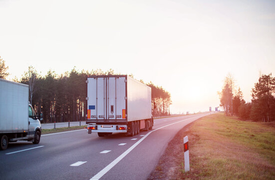 Trucks with a semi-trailer of 20 tons and a truck with a mass of 3.5 tons are transporting cargo on an evening road. Concept of logistics and business in cargo transportation, freight price. Copy
