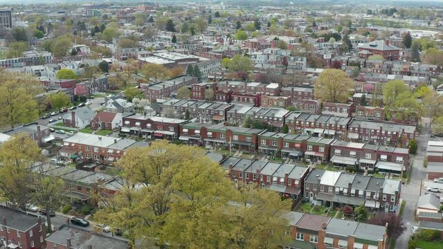 Aerial of urban city in USA during spring season. Establishing daytime shot. Homes and residences along town streets. Blooming trees.
