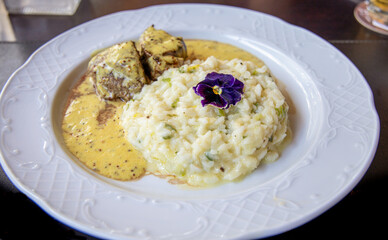Delicioso risoto servido com filé mignon ao molho de madeira em prato branco.