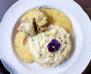 Delicioso risoto servido com filé mignon ao molho de madeira em prato branco.