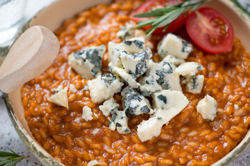 Close-up of red pesto sauce risotto topped with gorgonzola cheese, selective focus, horizontal shot