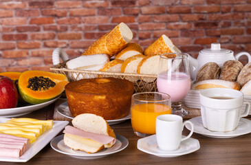 Mesa de café da manhã com vários alimentos, incluindo pães, doces, bolo, iogurte, chá, café,...