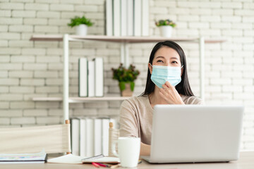 Beautiful young Asian woman wear surgical mask working from home and feeling happy smiling with joyful expression