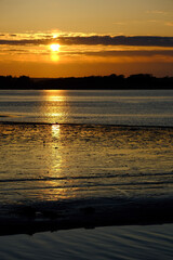 Beautiful  peaceful sunset over sea and land with a glowing orange sky.
