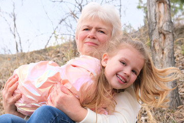 Loving cute granddaughter hugging her grandmother. Happy family.  Having good times with grandparent outdoors