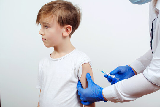 Pediatrician Makes Vaccination To Schoolboy In Clinic. Brave Child Receiving Injection Or Vaccine. Doctor Vaccinating A Child.