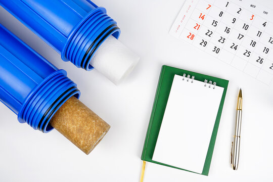 Blue housing water purifier pre-filter and cartridge. Changing the water filter of new. Notebook, calendar, Time for water filter replacement. FLAT LAY.