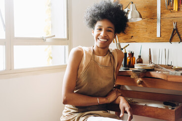 African woman smiling in her jewelry workshop