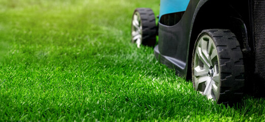 lawn mower cutting green grass. banner copy space