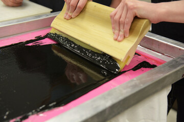 Screen printing, or silk screening, with black plastisol on t-shirts and posters.
