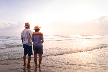 An elderly Asian couple Stand together on the beach Look at the beautiful sea in the morning...