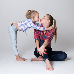 athletic mom and daughter show hair while sitting on chair and floor
