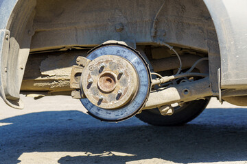 Closeup of disc brakes of a car raised by a jack without a wheel in tire service