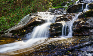 Obraz na płótnie Canvas Panoramic of fresh water waterfall coming down from the mountain in long exposure photo. Navacerrada Madrid.