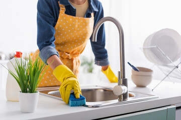 Cropped view of housewife with sponge cleaning sink in kitchen - obrazy, fototapety, plakaty