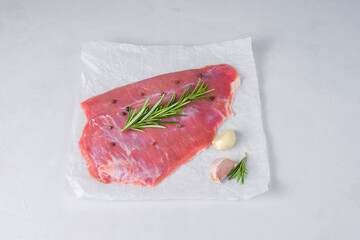 Fresh raw flank steak beef with rosemary, garlic, olive oil on light background. Classic marinades recipe for roasting or grilling. Meat food menu