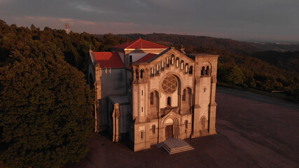 Fototapeta premium DRONE AERIAL VIEW: Facade of the church of Nossa Senhora da Assuncao (Our Lady of Assumption) in the hill of Monte Cordoba at sunset in Santo Tirso, Portugal.
