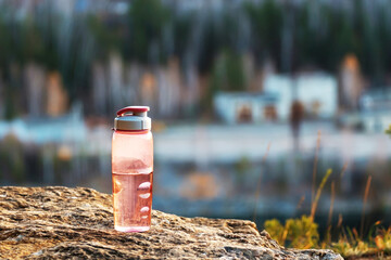 reusable plastic water bottle on a stone in the forest