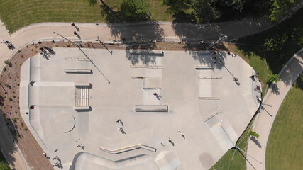 AERIAL DRONE VIEW - Amazing aerial view of the skate park in Santo Tirso city in Portugal with many skaters and bmx bikers on it. The Geao Urban Park with high school building in background.