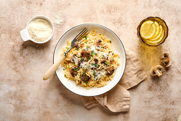 Dining italian pasta risoni, mushrooms, sauce, Parmesan, thyme, garlic, olive oil, in white plate over slate, stone or concrete background. Top view with copy space. Italian cuisine.
