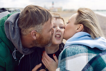Fototapeta premium family mom and father kiss teen son on the cheek