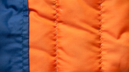 Abrigo de plumas naranja y azul usado textura