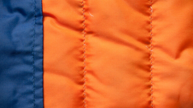 Abrigo de plumas naranja y azul usado textura
