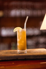 drink closeup with bar background standing on wooden plate with lamp on the left
