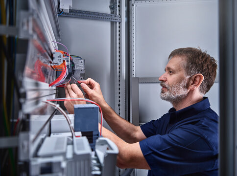 Male electrician examining power supply in electrical workshop