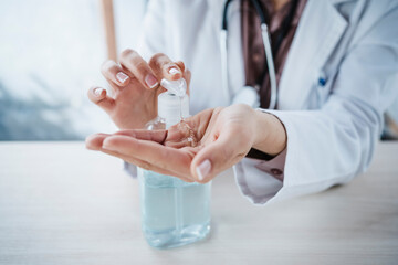 Female doctor using alcohol gel at desk