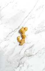 Flat lay bright food photography of a ginger root on a white marble board. Natural medicine and health diet concept.