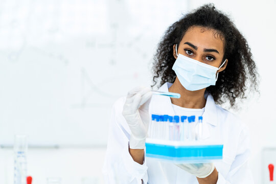 Female researcher holding microplate in laboratory during pandemic