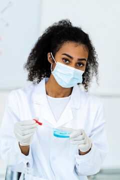 Female researcher in protective face mask working in laboratory