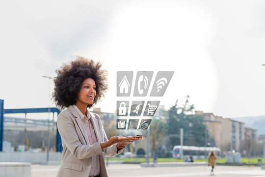 Businesswoman looking at mobile app coming through mobile phone in city