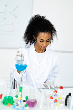 Female chemist using digital tablet while holding flask in laboratory