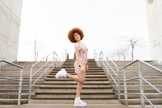 Young woman standing on one leg by railing