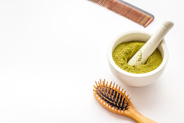 Henna hair dye powder and wooden comb. Henna in wtite mortar