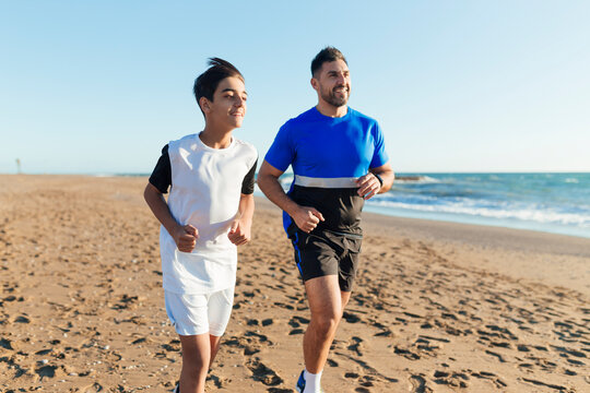 Smiling father and son running at beach