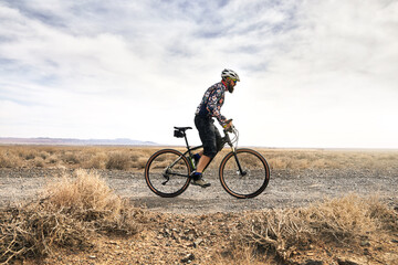 Fototapeta na wymiar Mountain biker rides at the desert scenic in Kazakhstan