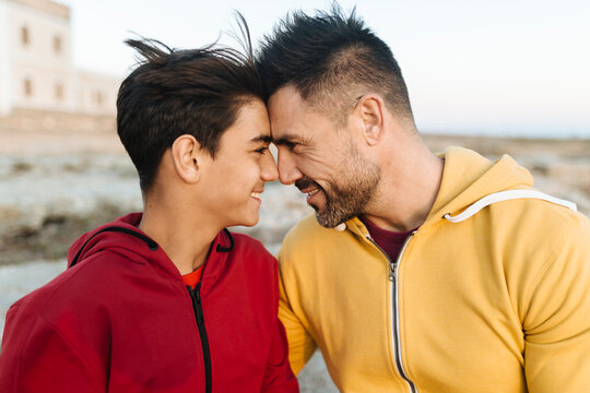 Smiling father and son touching forehead