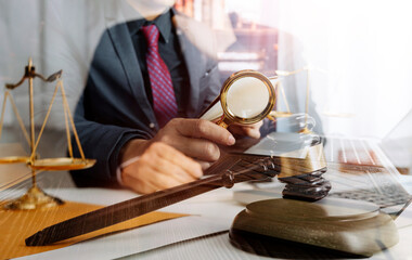 Justice and law concept.Male judge in a courtroom with the gavel, working with, computer and docking keyboard, eyeglasses, on table in morning light