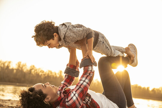 Playful mother picking up son while playing during sunset