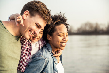 Cheerful parents with son by lake during sunset