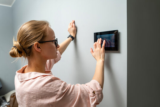 Young woman using home automation device while standing by wall at home