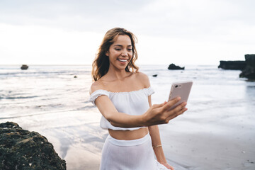 Smiling woman taking selfie at seaside