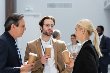successful businesspeople holding paper cups during conversation on coffee break