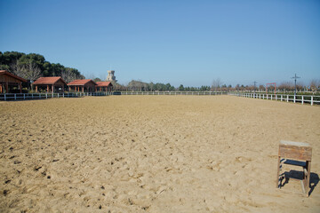 Fototapeta na wymiar A large arena with sand for horses . Elite Horse and Polo Club . training ground. horse club. Sand Stadium for horseback riding. Horse home .