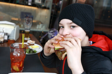 Kid eating burger on restaurant terrace